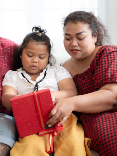 An overweight family open a gift while sitting on the couch 