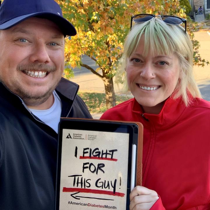 husband and wife holding up small sign that says I fight for this guy